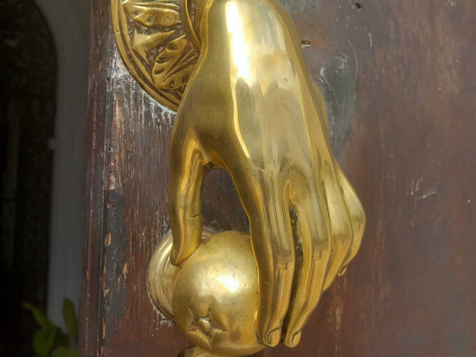 Schöner bronze farbener zarter weiblicher Türklopfer, der eine Orange hält.